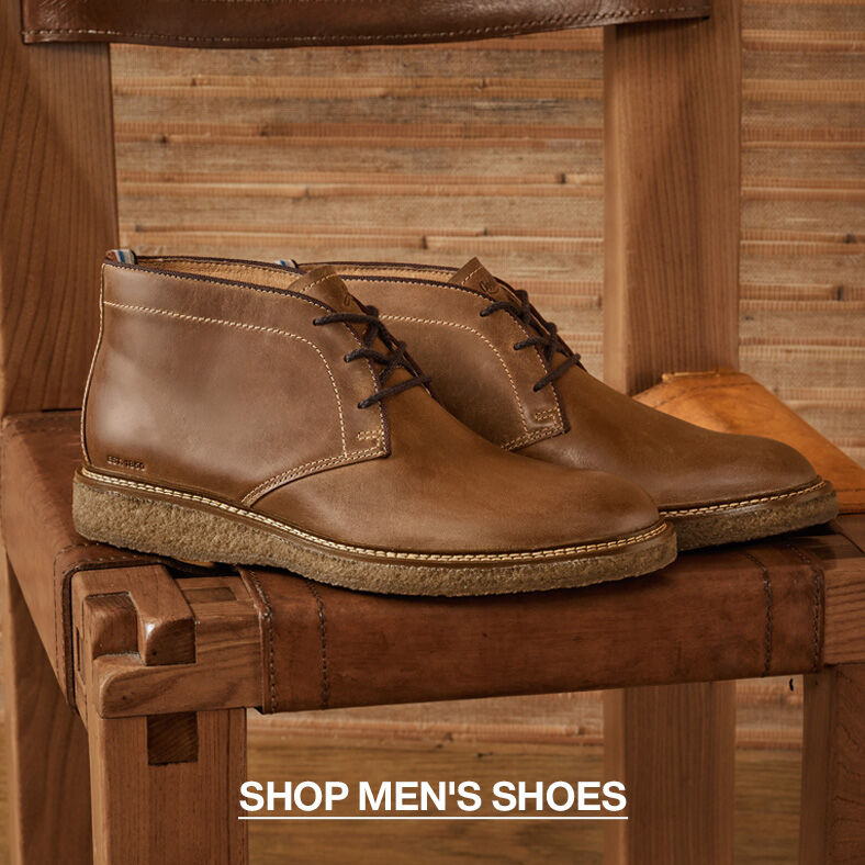 Pair of light brown men's cukka boots sitting on a natural wood colored chair. Click through to Shop Men's Shoe's.